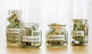 Four glass jars of various sizes with cash and coins inside.
