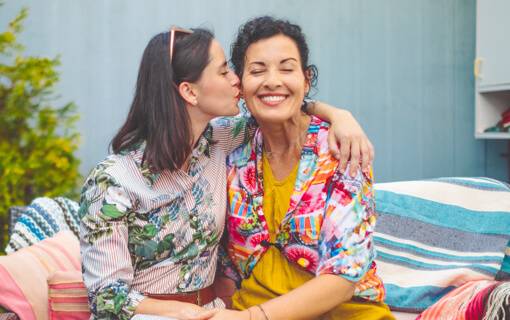 Adult daugther kisses her mother on the cheek
