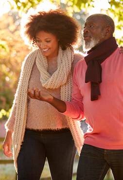 Adult woman walks outside with her elderly father