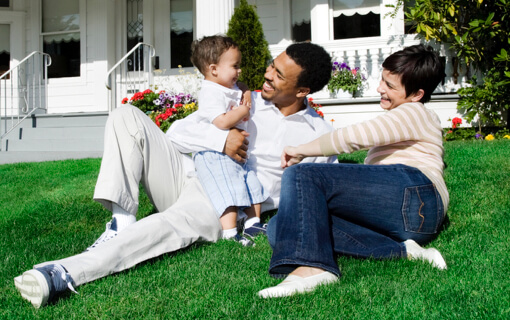Mother and father play with toddler on their front lawn