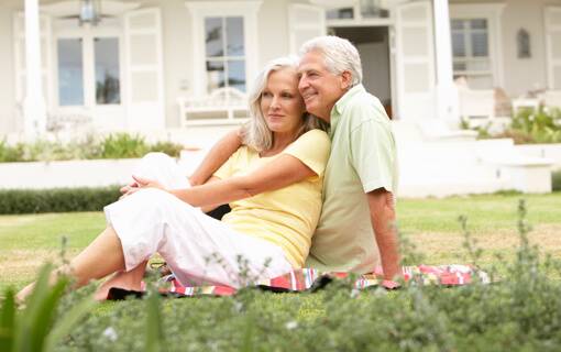 Senior couple laying together on their front lawn