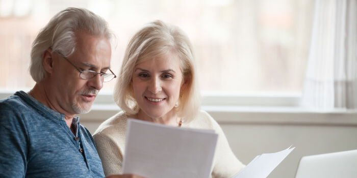 older couple smiling reviewing documents