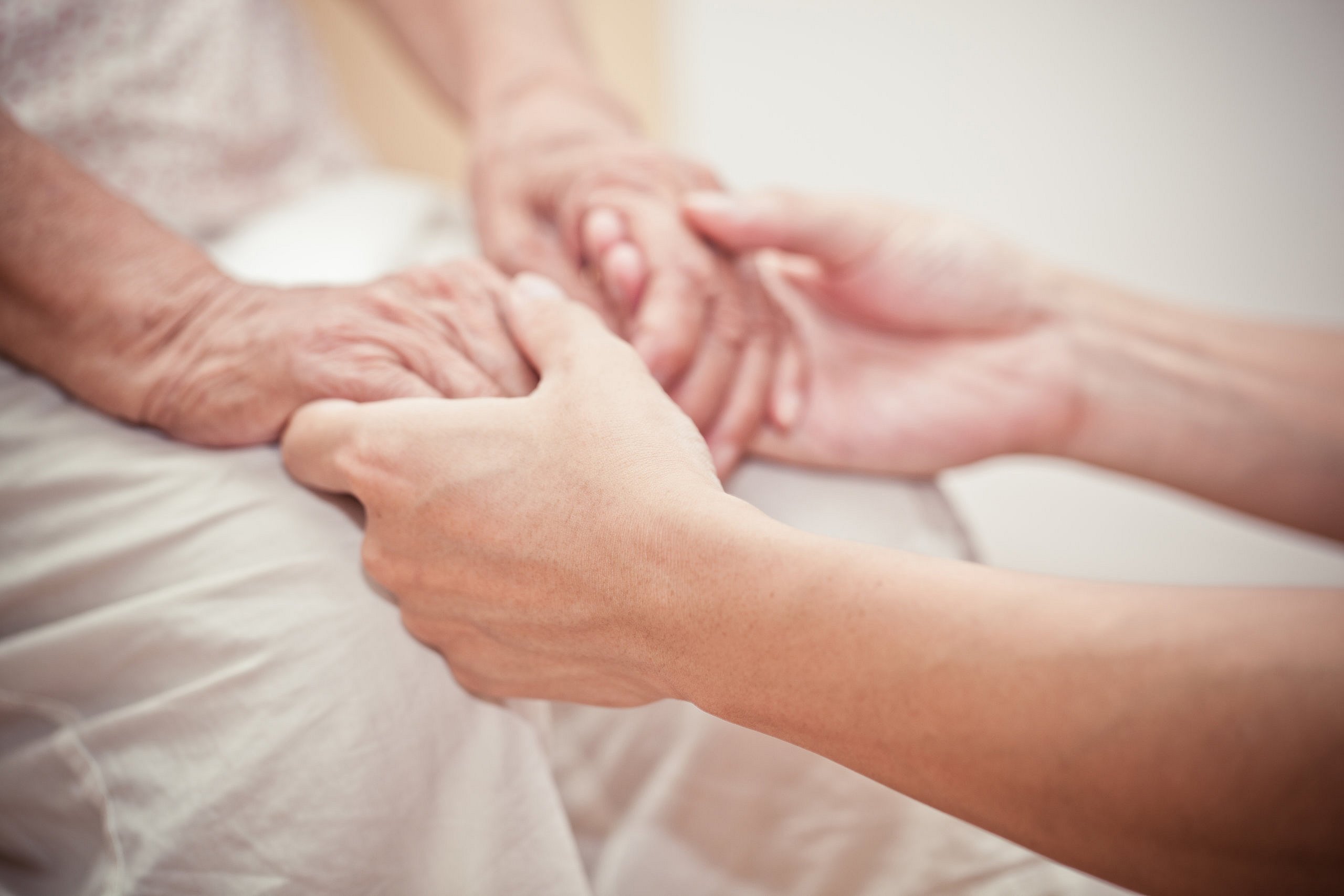 Woman with Alzheimer's holding loved one's hands.