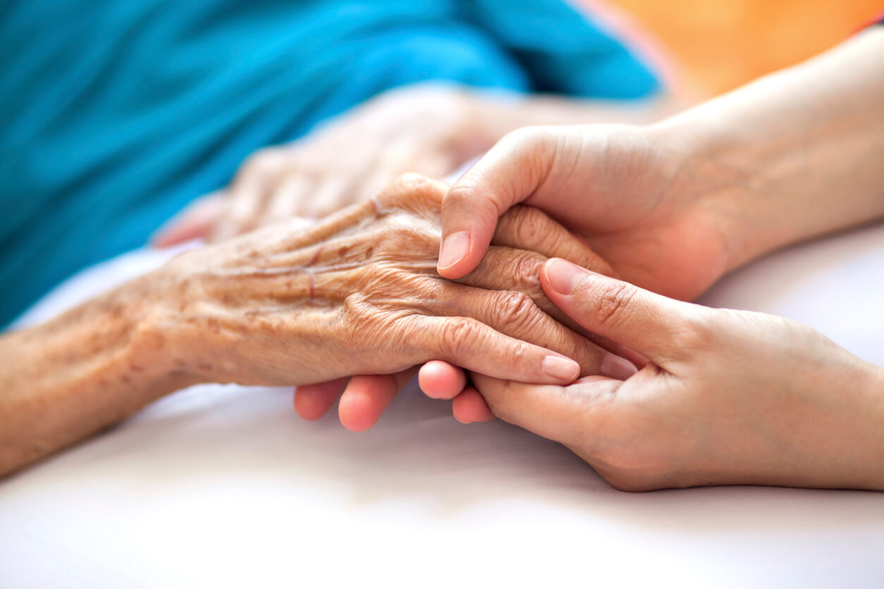 Elderly woman holding the hand of her personal representative.