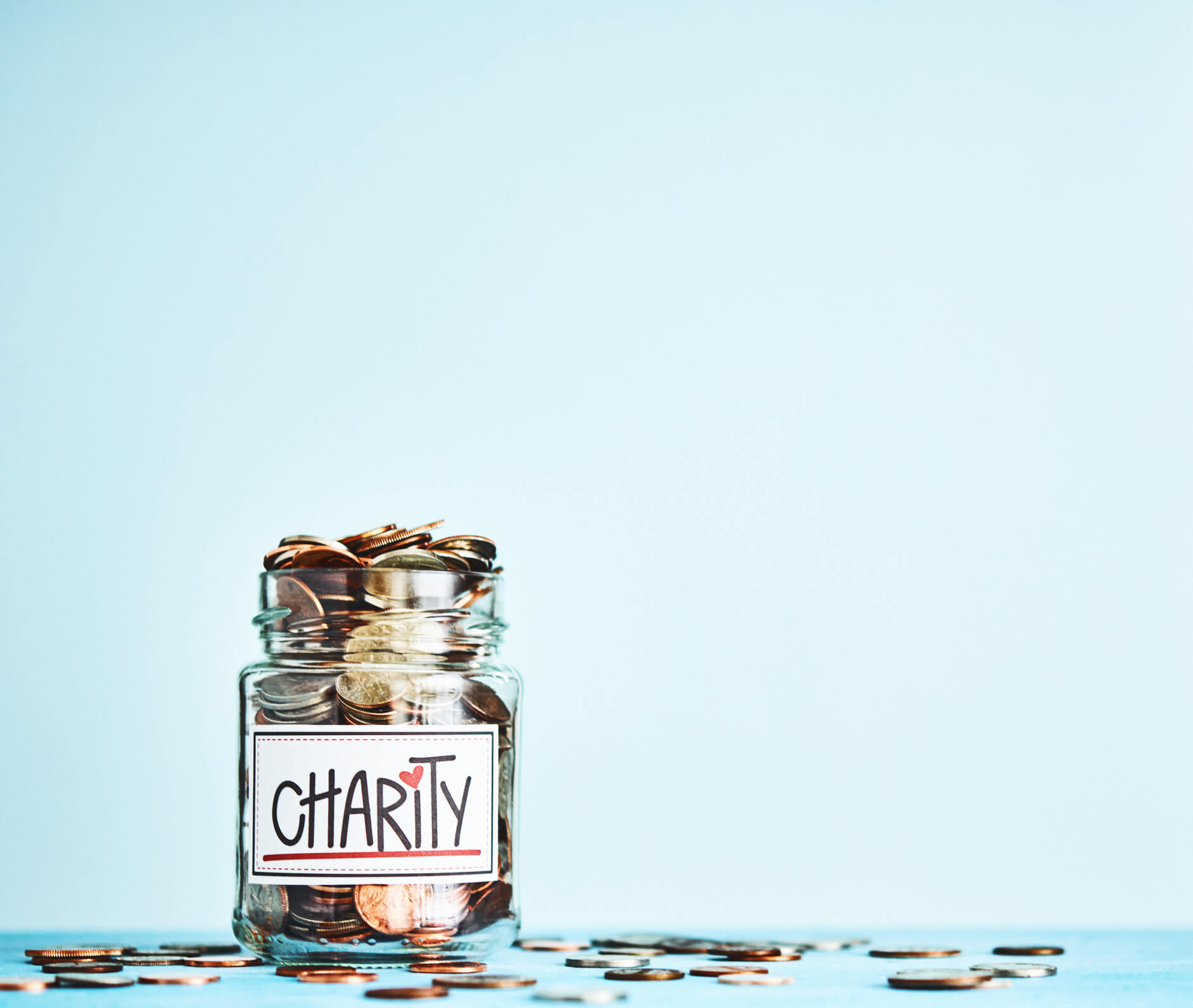 Jar of coins over blue background - representing charitable giving.