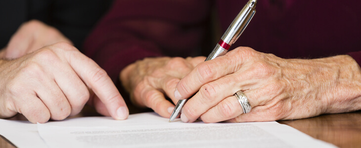 elderly person signing a document