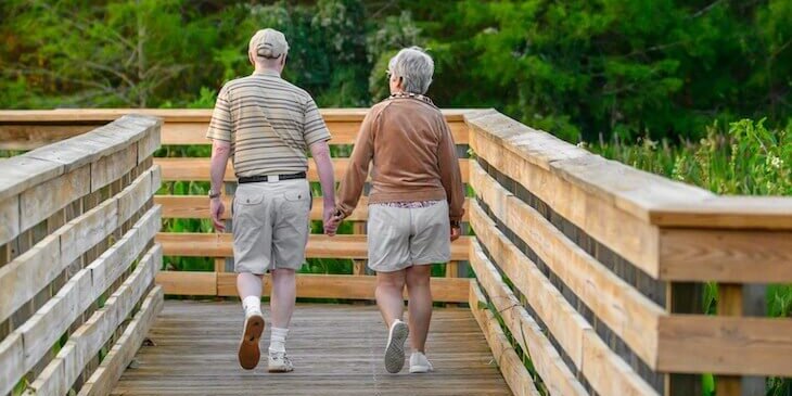 seniors walking along pier holding hands
