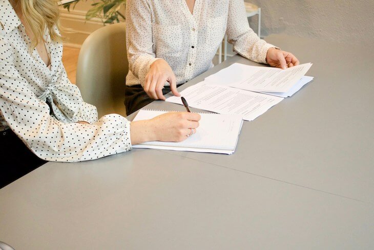 two women sitting at table reviewing legal documents