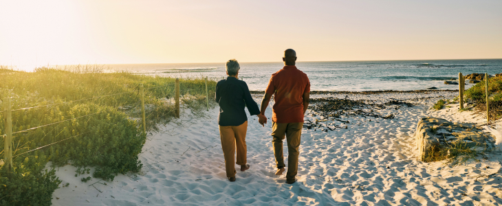 Gen X couple holding hands walking on the beach