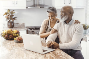 Gen x couple smiling while looking at a laptop