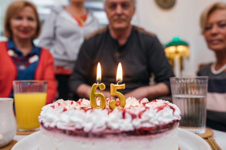 Burning candles with number 65 on cake.