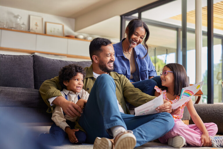 Creative happy smiling daughter showing artwork to family in living room.