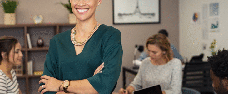 A smiling female team leader stands in a busy office. Image from Surprenant, Beneski & Nunes.