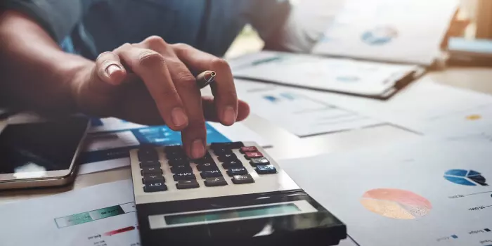 man with calculator reviewing information sheets