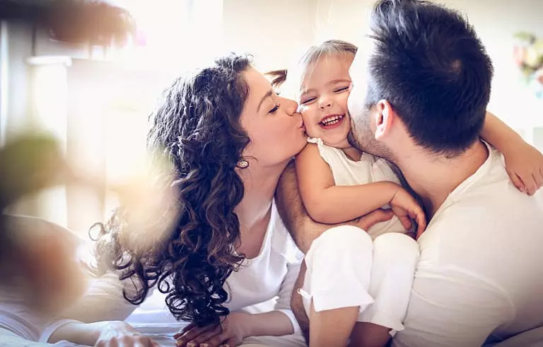 Young family hugging their daughter.