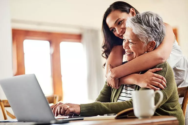 Daughter hugging elderly mother on the computer.