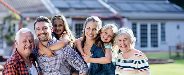3 generational family taking a photo behind their house