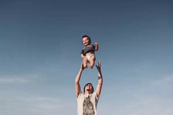 a happy father tossing his baby up