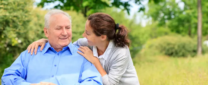 Older man in a wheel chair being pushed by young woman