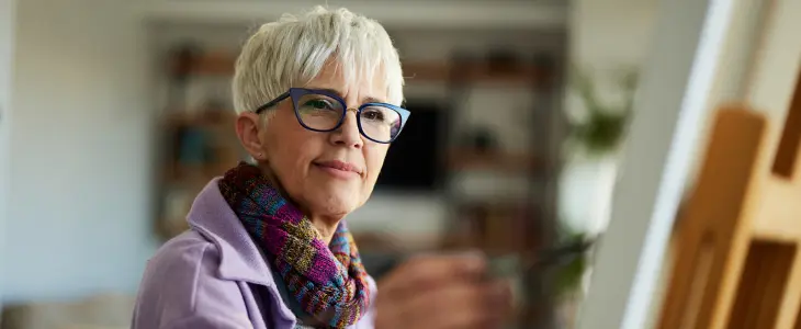 Elderly woman painting on a canvas