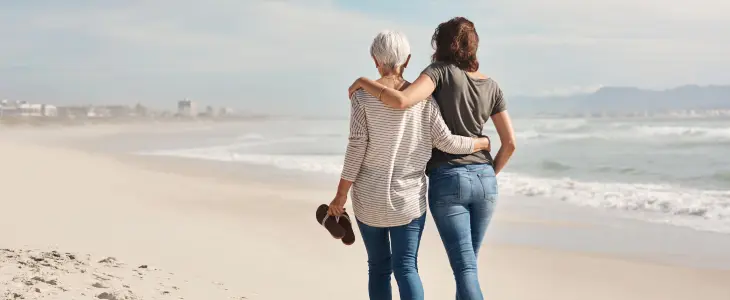 Mother and daughter walking along a beach