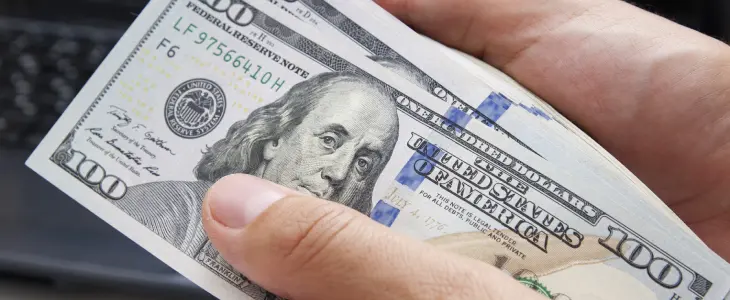 close up of someone holding one hundred dollar bills