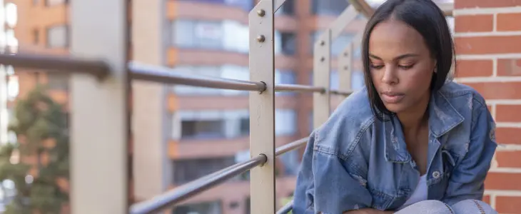 Woman sitting on a balcony looking sad