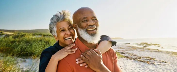 Gen X couple standing on a beach while hugging each other