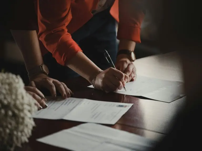 Person signing legal documents on a table.