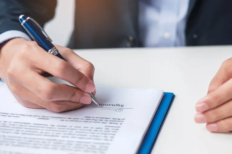 man signing on contract documents