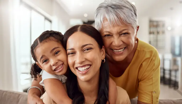 Child, mother and grandmother portrait while at home on sofa with smile, love and support sharing hug for generation of senior, woman and child. Portrait of brazil girls happy on mothers day together