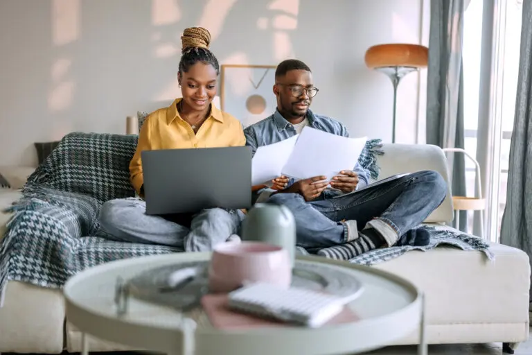Young smiling couple going over paperwork while sitting on the sofa