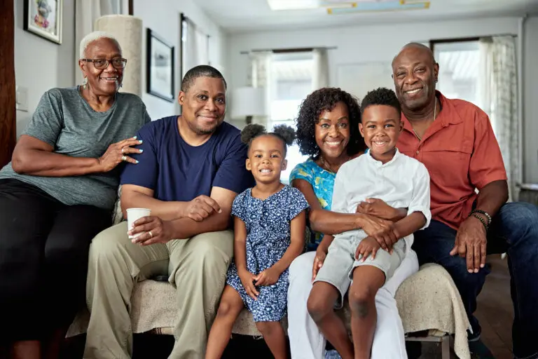 Front view of children aged 4 and 7 with their parents in 40s and 50s and grandparents in late 60s, all casually dressed and smiling at camera.