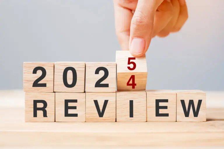 hand flipping block 2024 to 2025 REVIEW text on table.